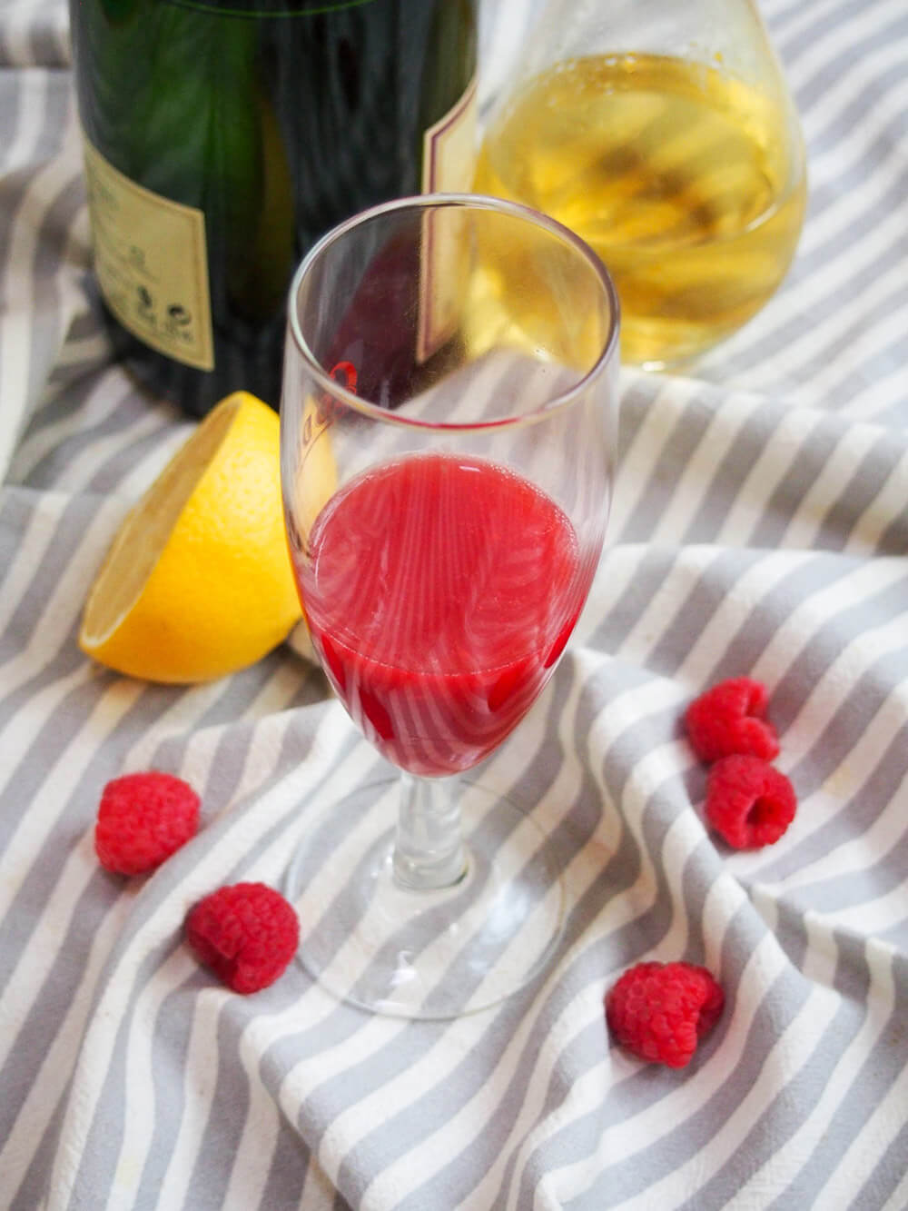 raspberry puree in glass, ready to top up, with limoncello and champagne bottles behind