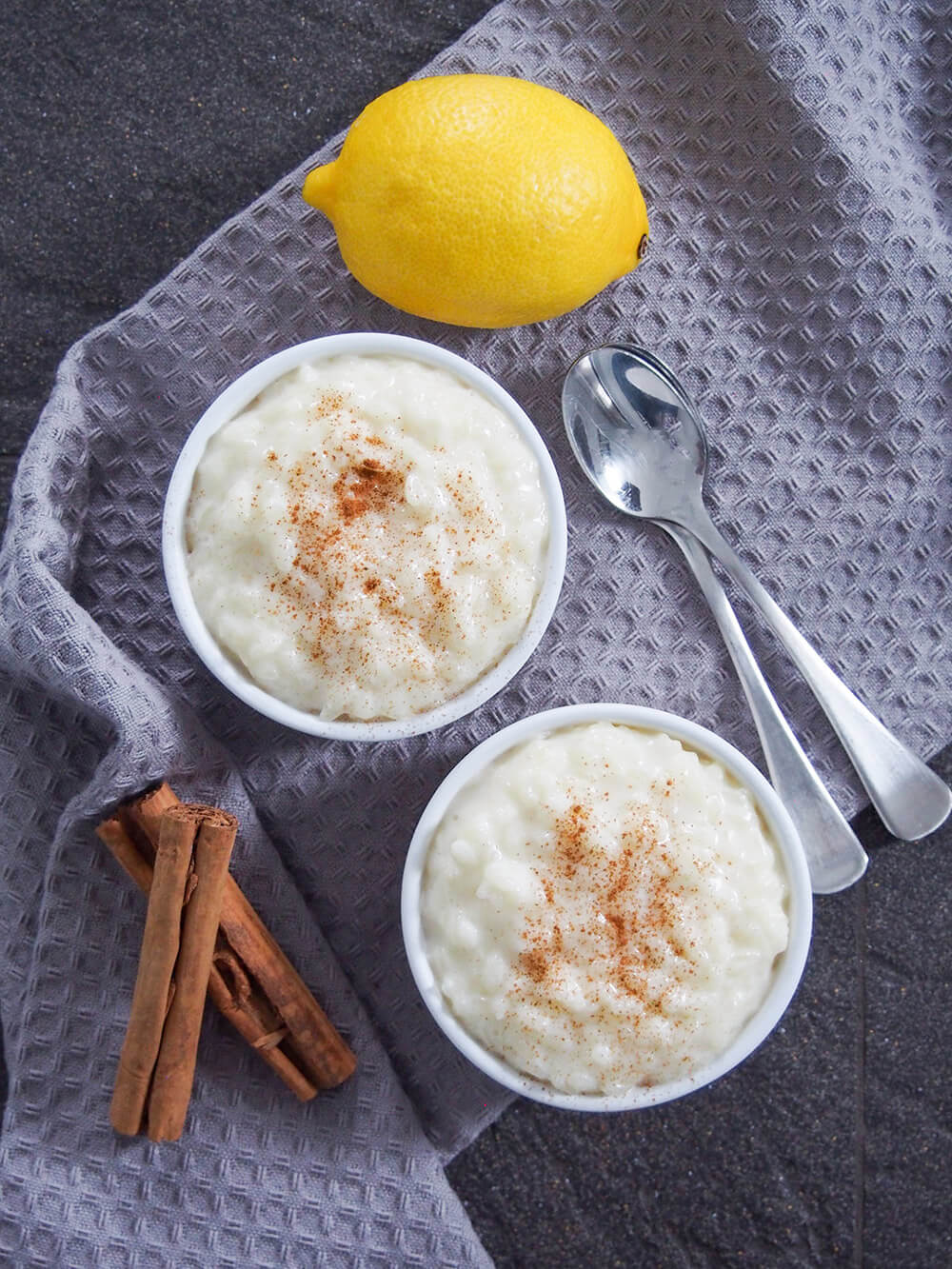 Two bowls of Arroz con leche (Spanish rice pudding) with spoons to side