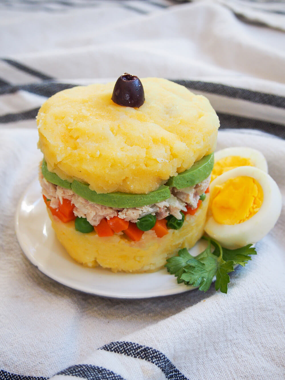 serving of causa rellena with boiled egg to side and olive on top