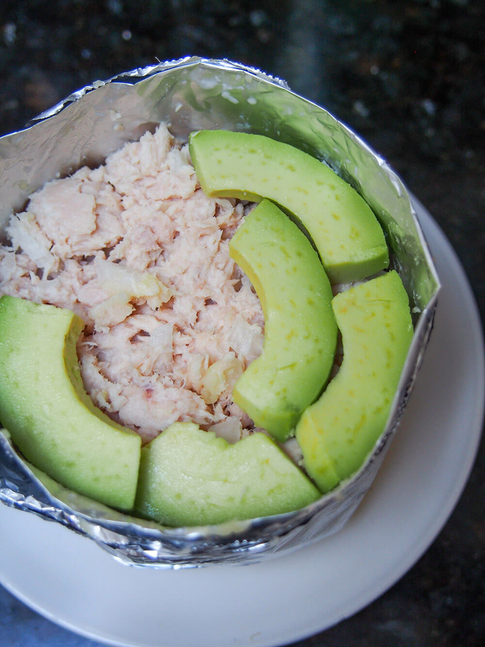 adding filling layers to causa rellena - here layering avocado over the tuna