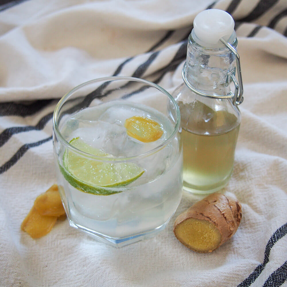 glass of homemade ginger ale with bottle of syrup to side