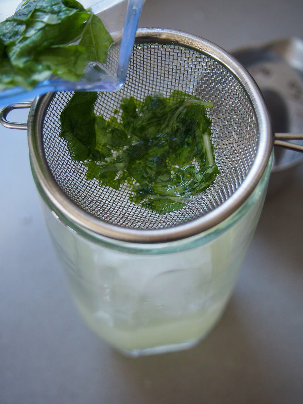 straining drink into glass of ice
