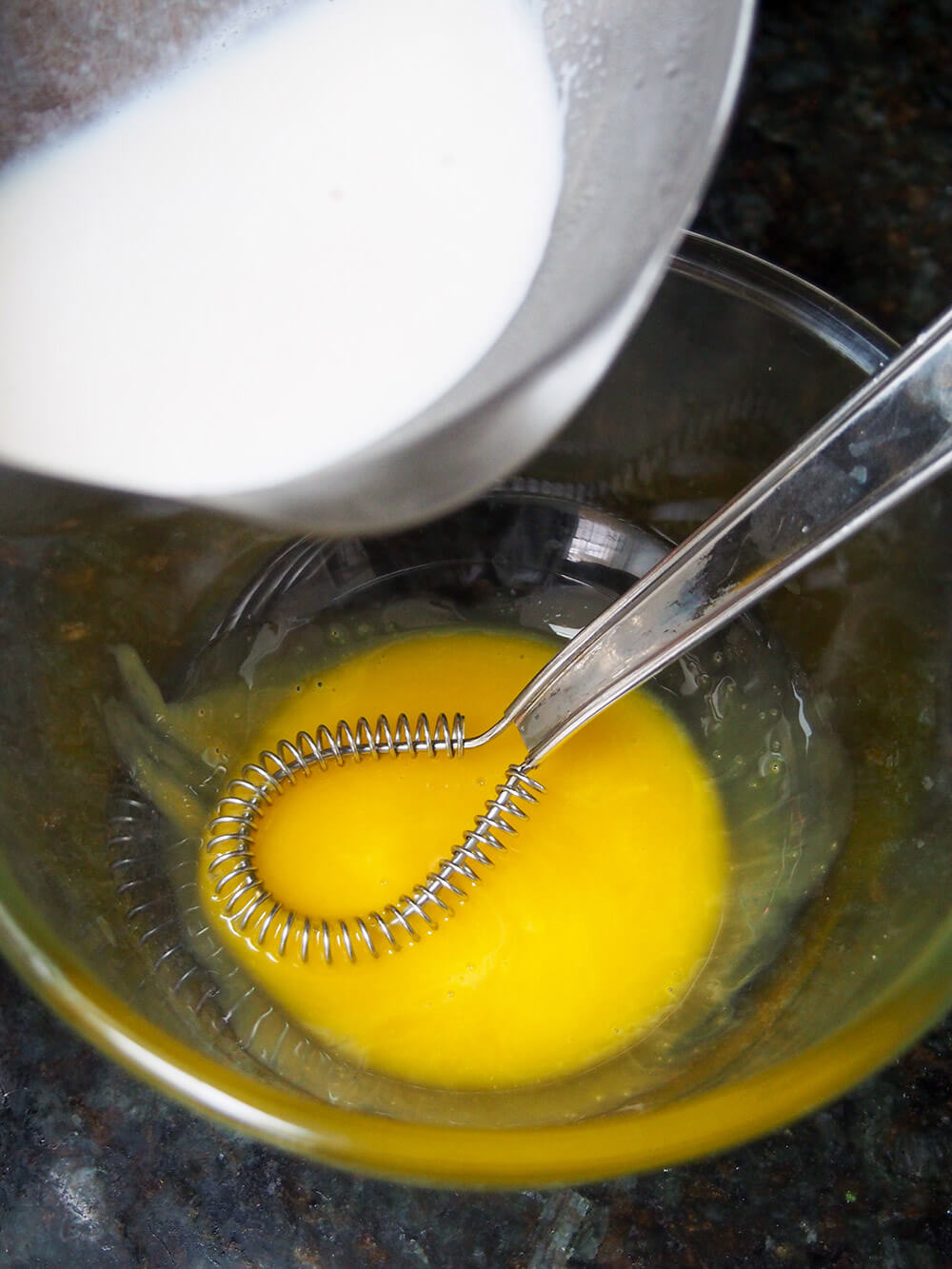 adding warm milk to egg
