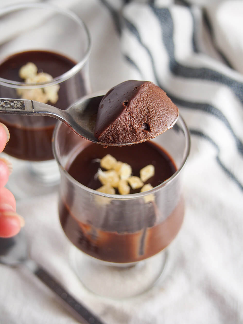 spoonful of custard held above glass