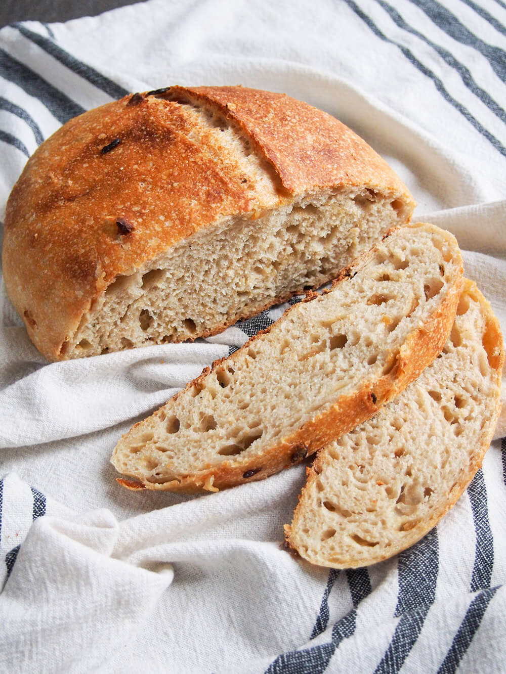 two slices of sage and caramelized onion sourdough bread in front of rest of loaf