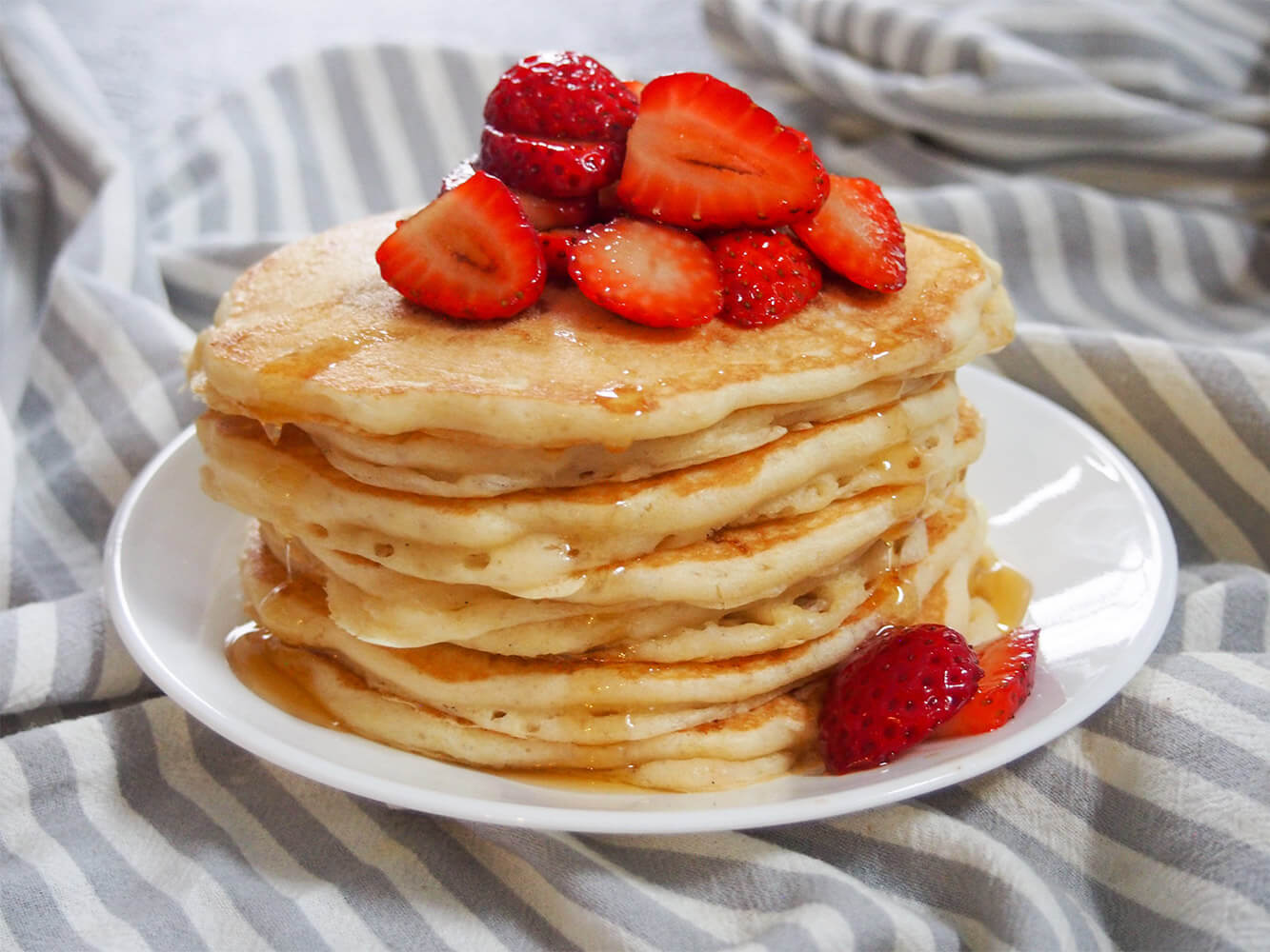These sourdough pancakes are not only a great way to use sourdough discard, they taste amazing. Incredibly light and fluffy, they're also so easy to make. stack of sourdough pancakes with strawberries on top