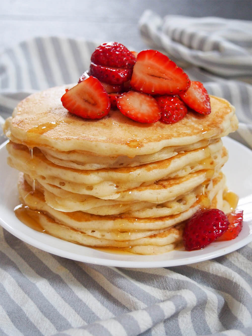 These sourdough pancakes are not only a great way to use sourdough discard, they taste amazing. Incredibly light and fluffy, they're also so easy to make. stack of sourdough pancakes with dripping syrup and topped with strawberries