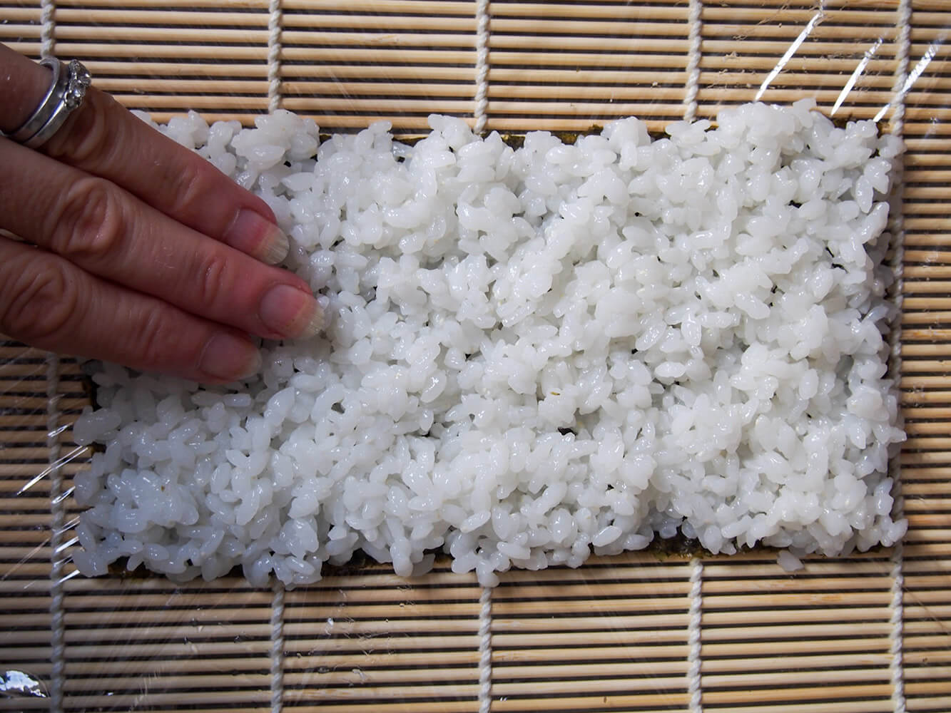 pressing rice on to seaweed sheet