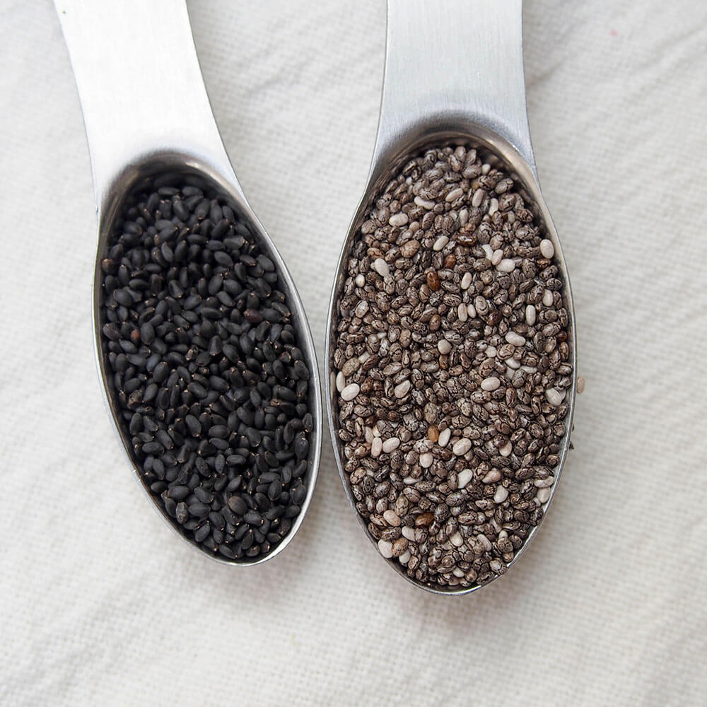 basil seeds in spoon on left compared to chia seeds in spoon on left