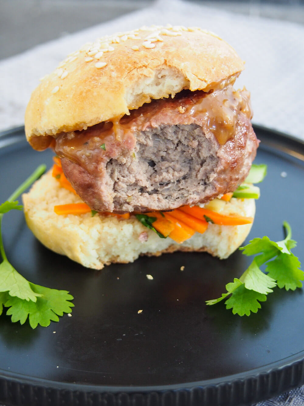 chicken satay burger with bite taken out of it