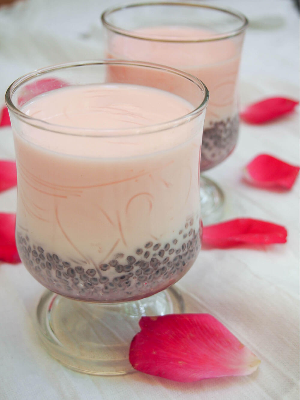 glass of falooda showing basil seeds and vermicelli in mixture through glass
