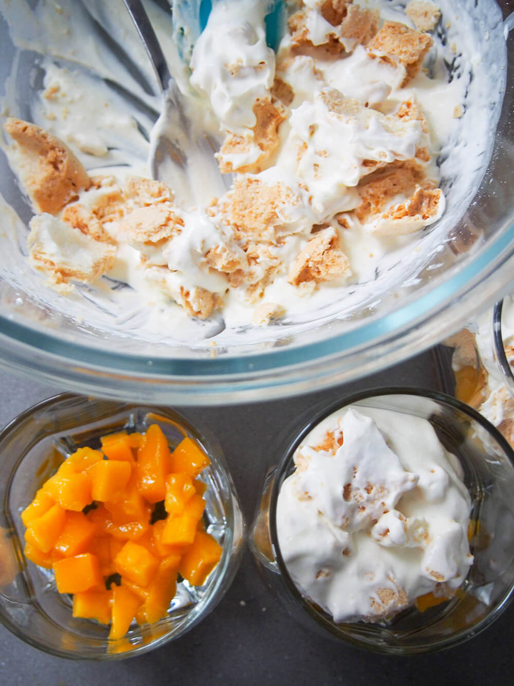 layering up glasses of fruit with cream and meringue mixture from bowl