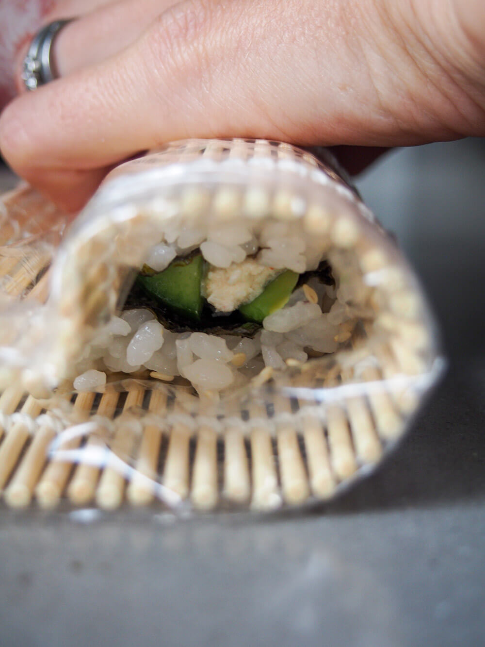 rolling California roll with a bamboo sushi rolling mat