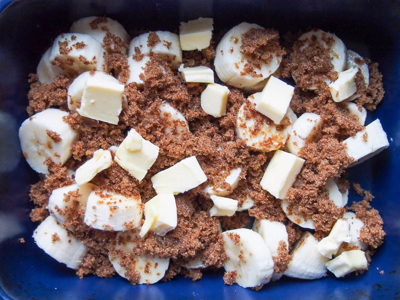 sliced banana, brown sugar and butter in baking dish