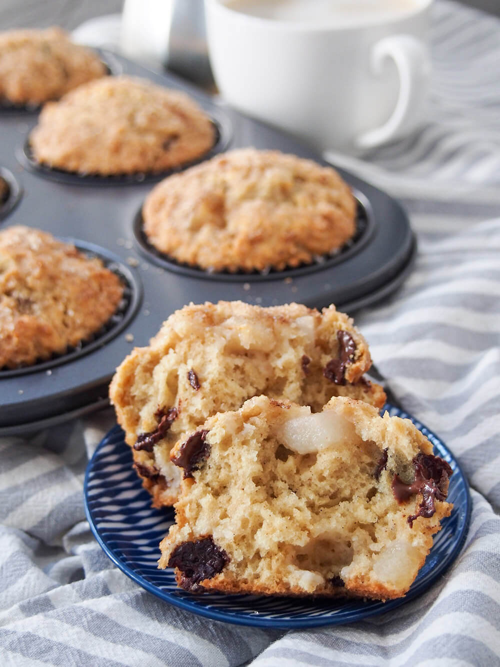 one muffin in front of others split open to show pieces of chocolate and pear 