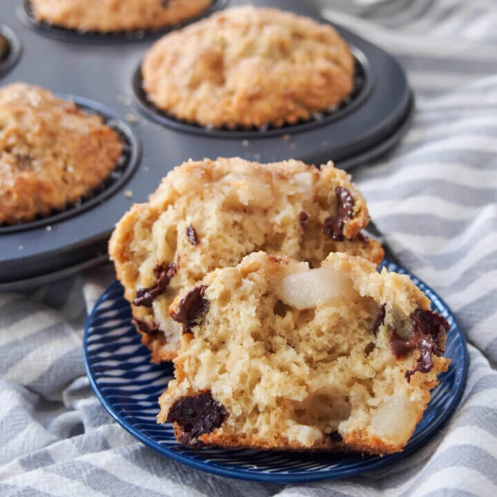 pear chocolate chip sourdough muffin split open in front of tin with more