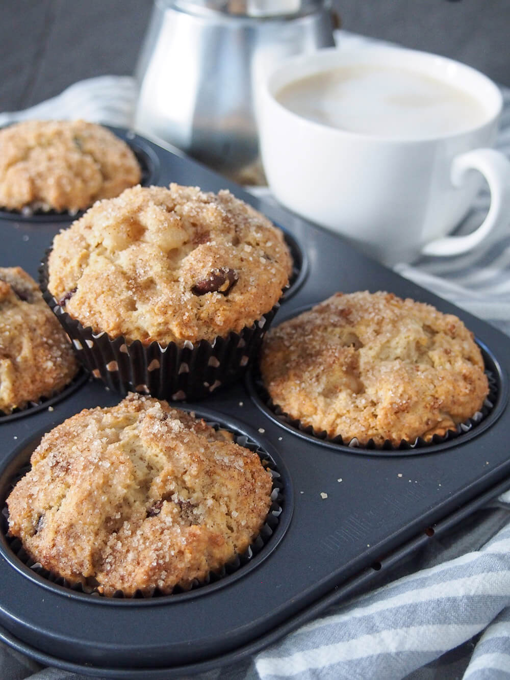 Pear chocolate chip sourdough muffins with one sitting on top of tin, others in tin