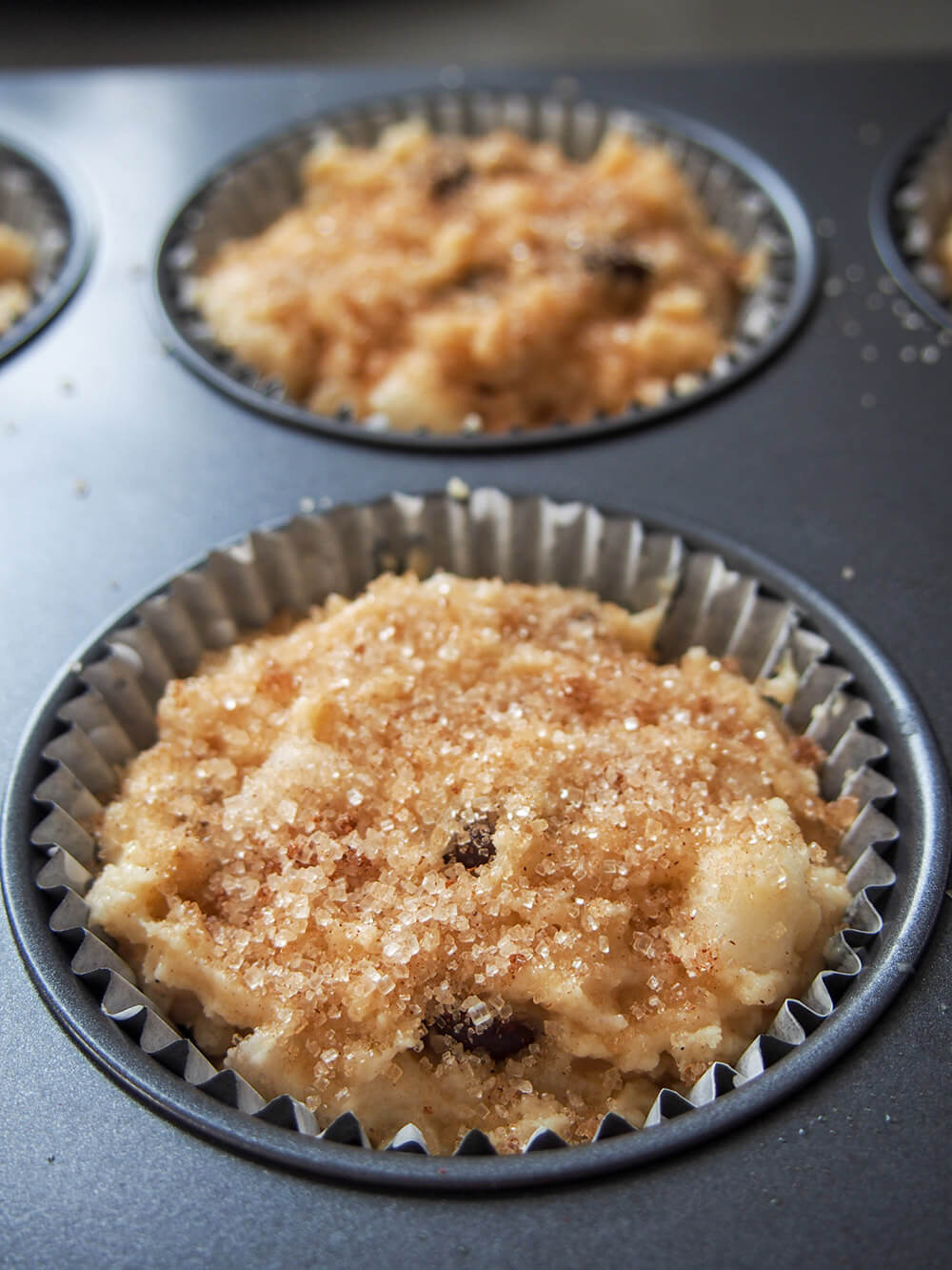 Pear chocolate chip sourdough muffins with cinnamon sugar sprinkled on top, ready to bake