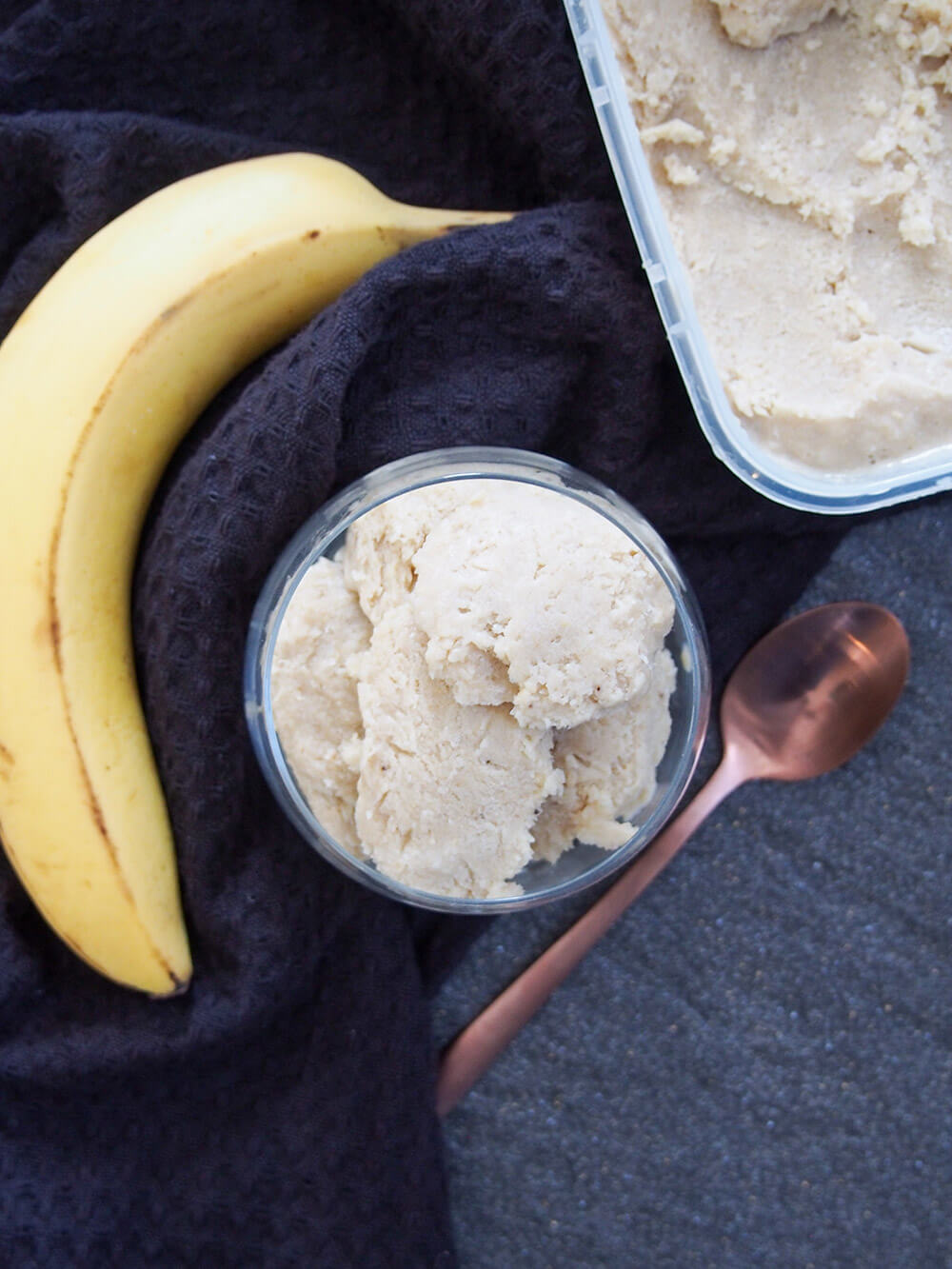 Roasted banana ice cream in glass and container with rest of ice cream from overhead