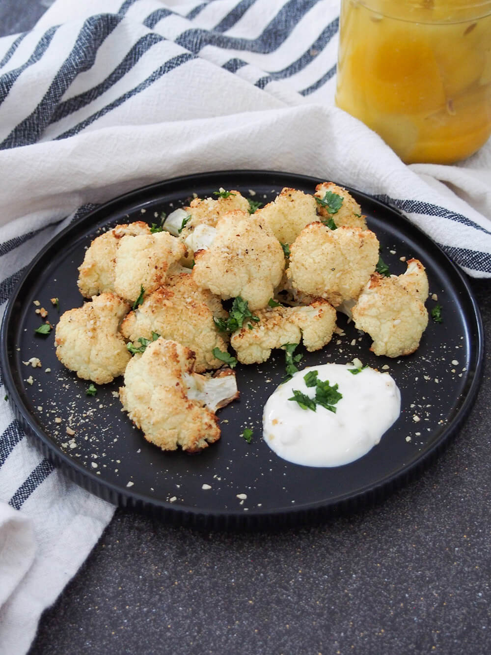 plate of dukkah roasted cauliflower with some preserved lemons behind