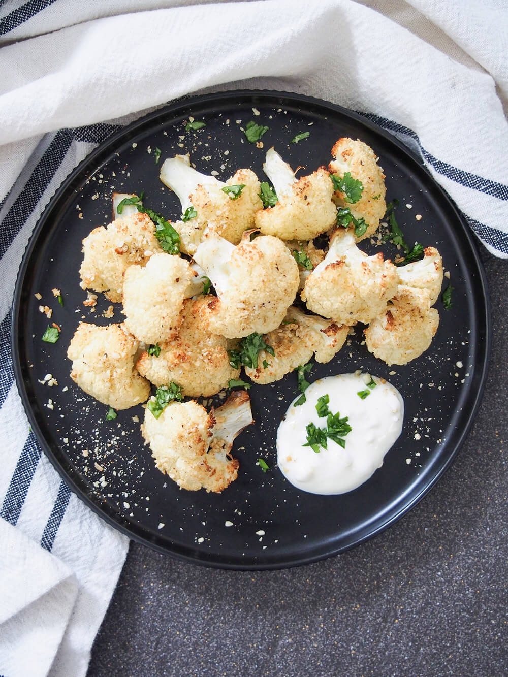 dukkah roasted cauliflower on plate viewed from overhead with preserved lemon yogurt to side