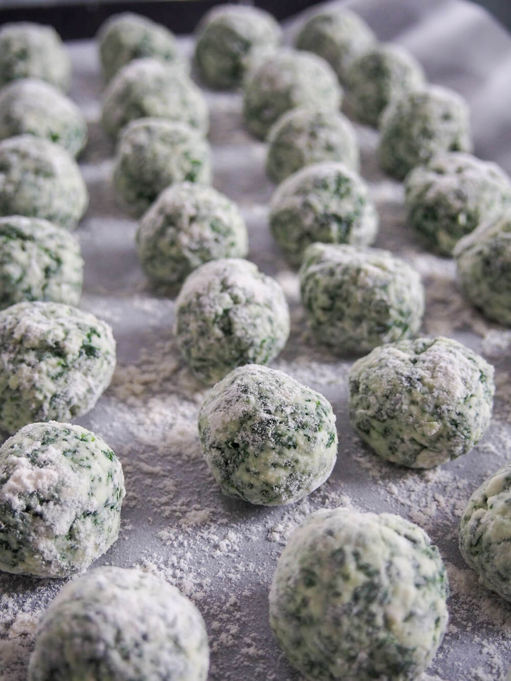 formed ricotta and spinach gnudi before cooking formed gnudi on lined baking sheet before cooking