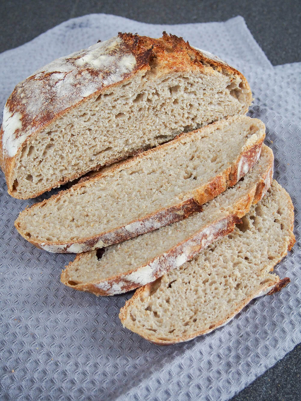 loaf of French country bread with a few slices cut sitting in front of rest of loaf