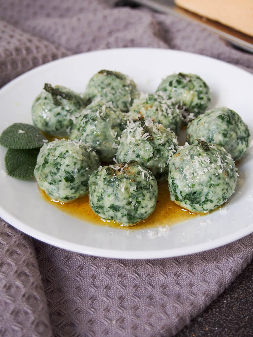 Ricotta and spinach gnudi are a little like gnocchi without the potato. They're light, cheesy and incredibly comforting and delicious! Ricotta and spinach gnudi on plate with parmesan on top