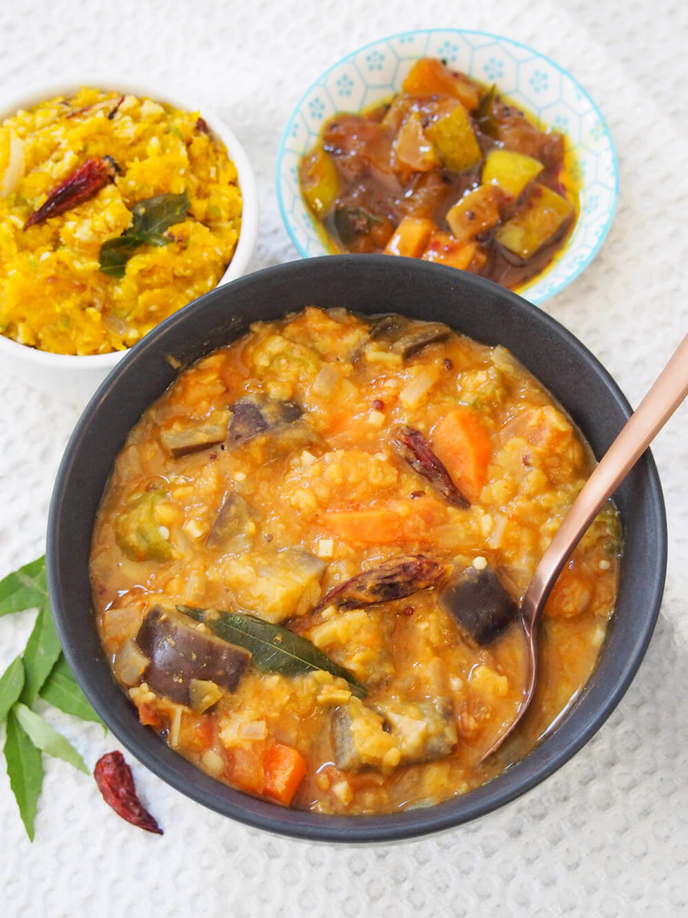 bowl of Kerala style sambar with sides of pickle and pumpkin erissery