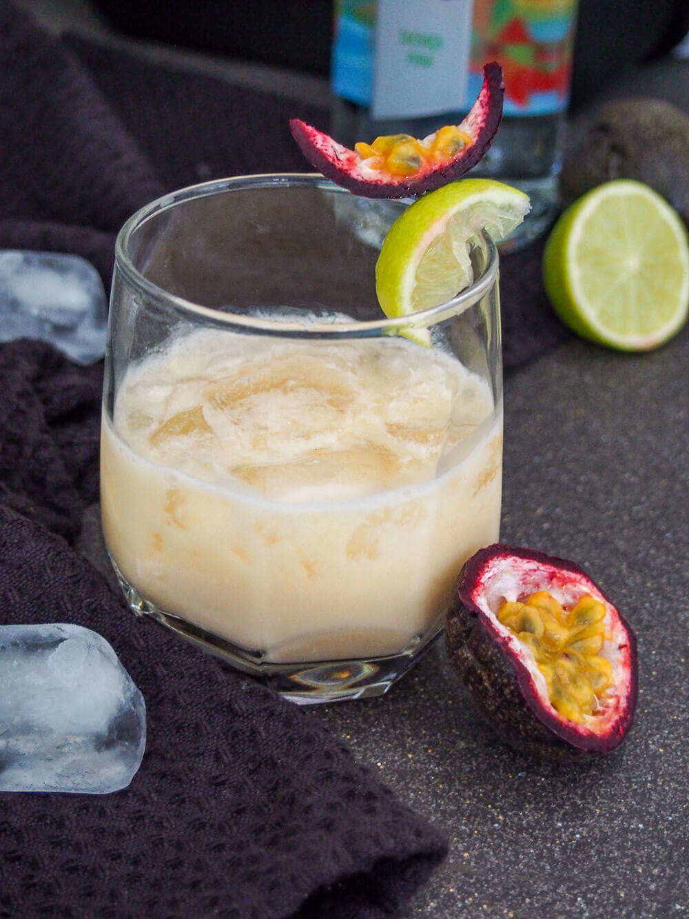 A batida is a popular cachaça cocktail in Brazil that's strangely less well known elsewhere. It's easy to make, sweet-tart and refreshing and perfect for sipping on a warm day. glass of finished cocktail with bottle of cachaca behind and passion fruit and ice cubes to side of glass