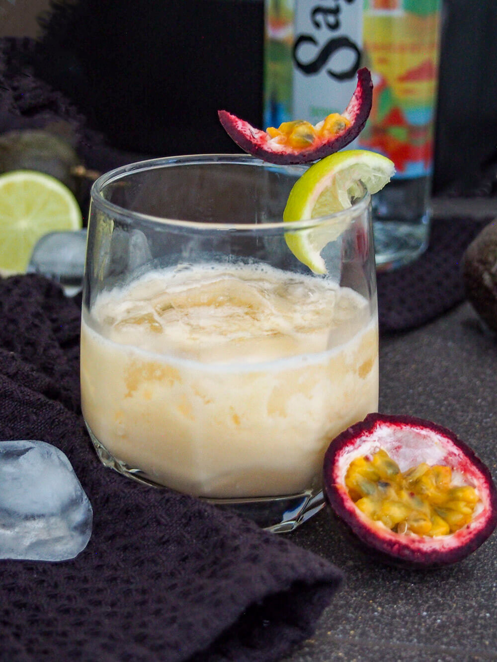 A batida is a popular cachaça cocktail in Brazil that's strangely less well known elsewhere. It's easy to make, sweet-tart and refreshing and perfect for sipping on a warm day. glass of batida with bottle of cachaca behind and passion fruit to side of glass