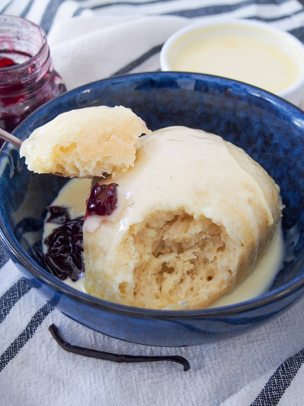 Dampfnudel is a steamed German sweet dumpling that's almost like a sweet bread, served with a luscious vanilla custard and often fruit compote. It's hearty but wonderfully comforting and delicious. dampfnudel with spoonful taken out of it