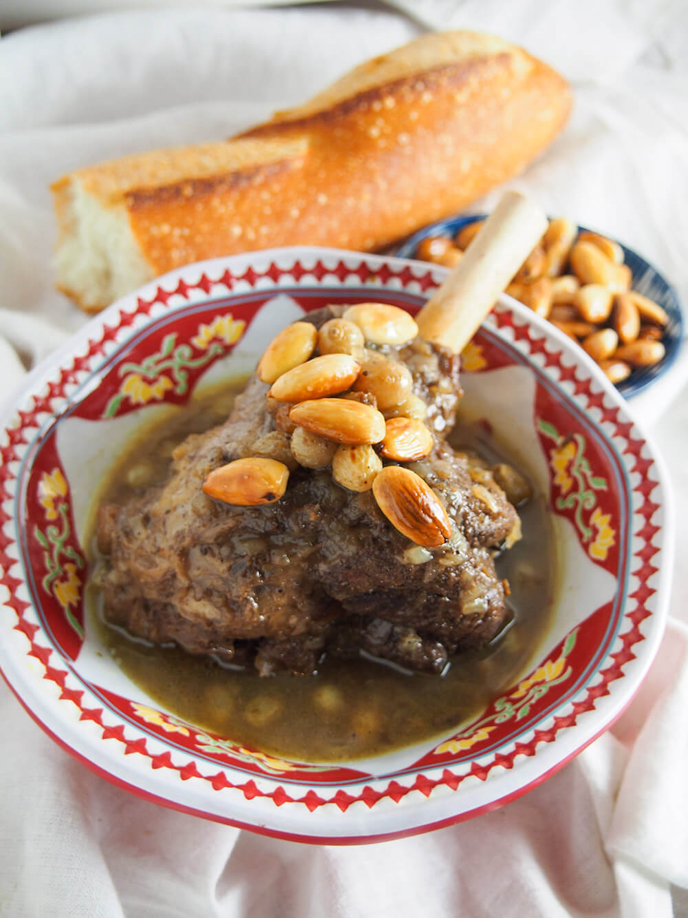 mrouzia honey lamb tagine in bowl with bread and almonds behind