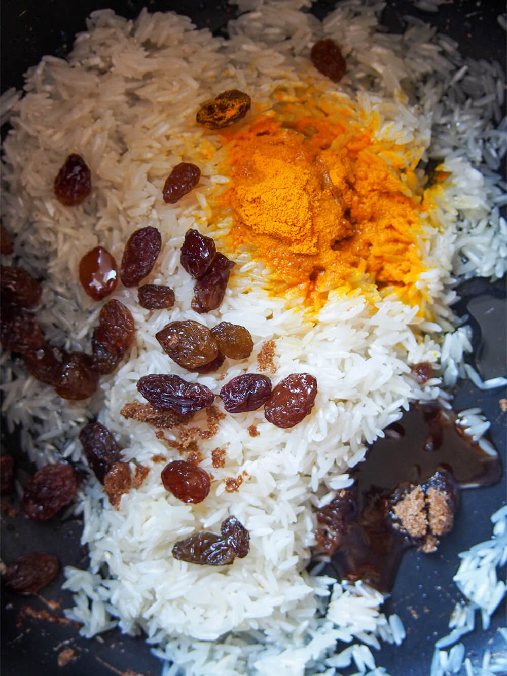 rinsed rice, turmeric, raisins and sugar in pot before cooking