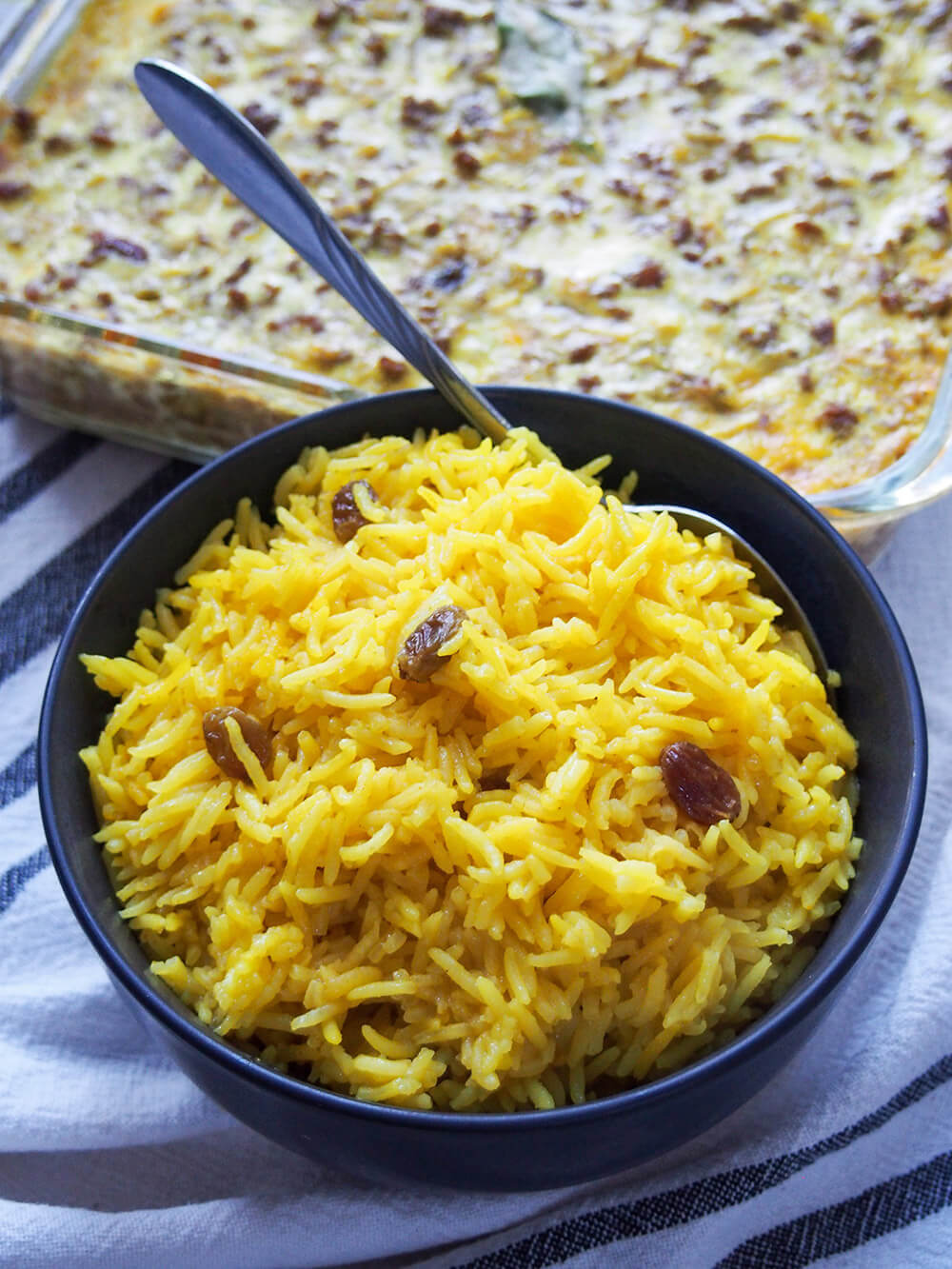 bowl of South African yellow rice with spoon standing up at back of bowl