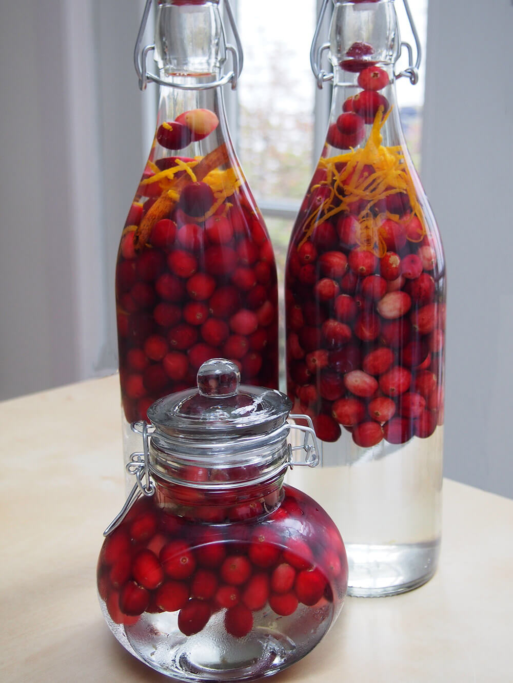 bottles with cranberries, aromatics and gin right after bottling