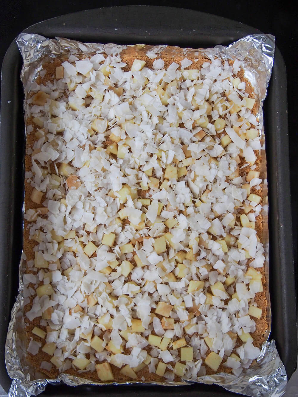 adding apple chunks and coconut to graham cracker base