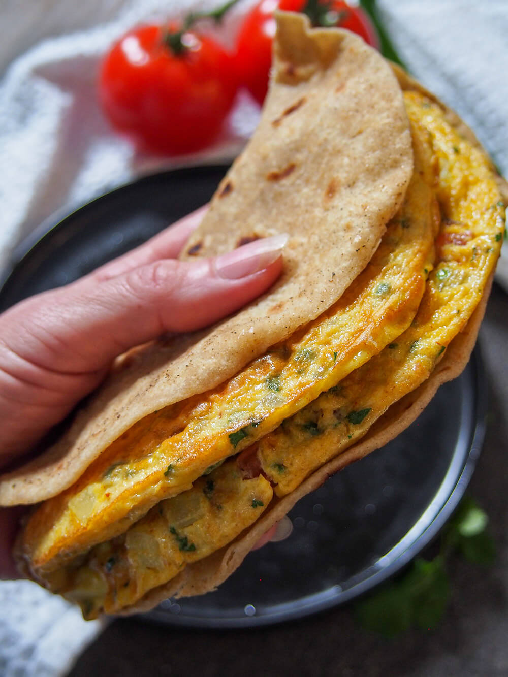 masala omelette held in hand in roti masala omelette held in hand in roti