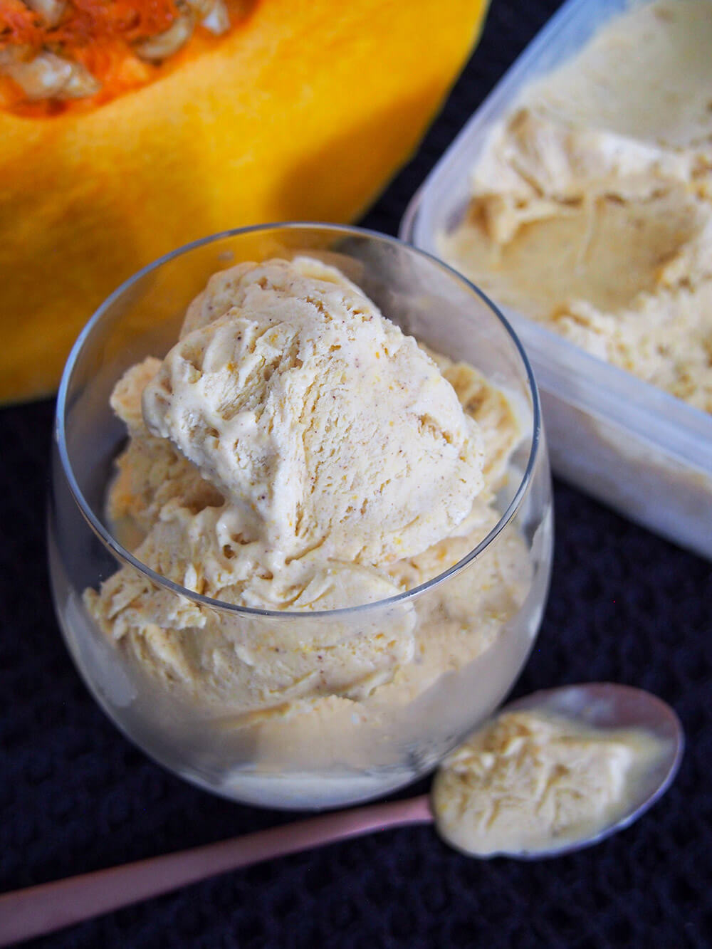 no churn pumpkin ice cream in glass with tub and piece of pumpkin behind