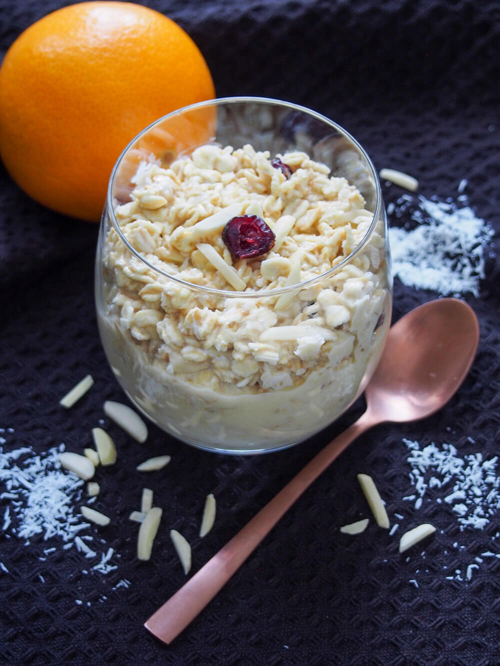 glass of orange overnight oats with spoon to side and orange behind