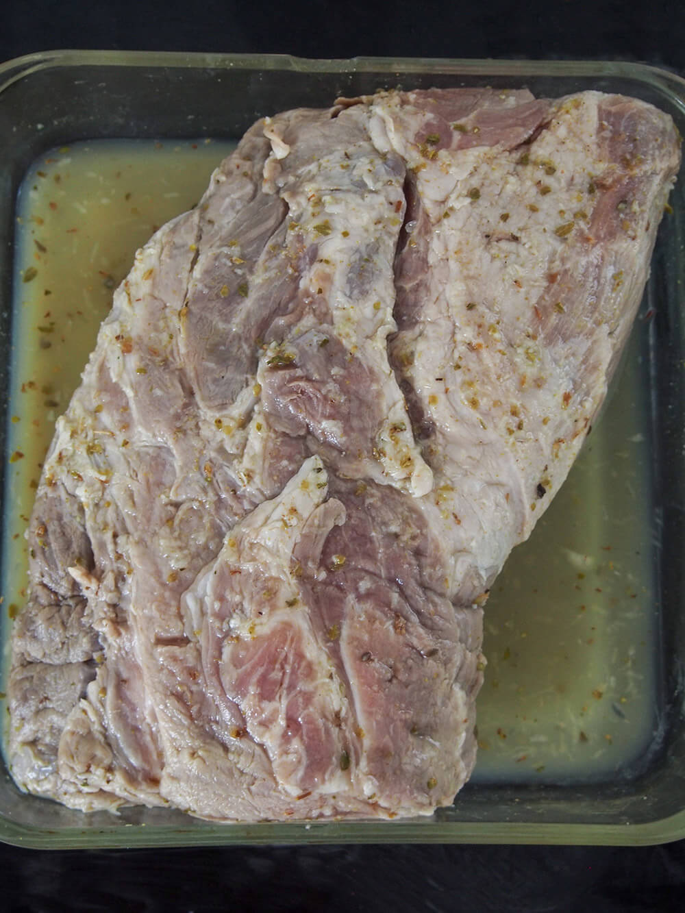 marinated pork in roasting dish with some sauce ready to roast