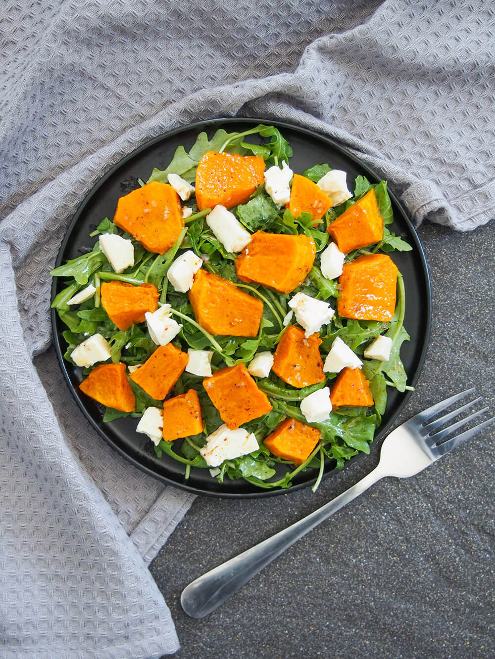 plate of roasted kabocha squash salad with feta from overhead with fork to side