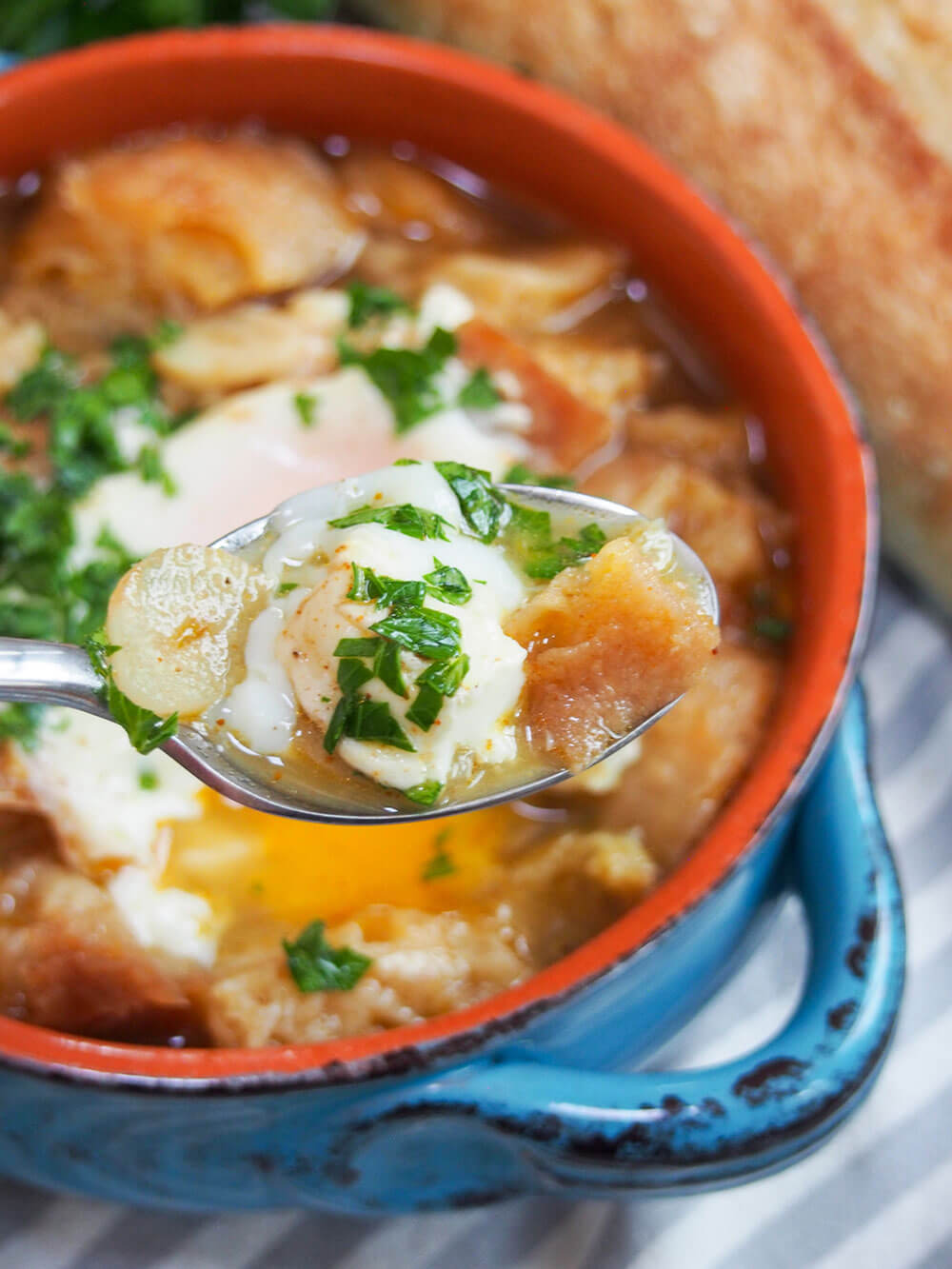 holding spoonful of soup above bowl with rest