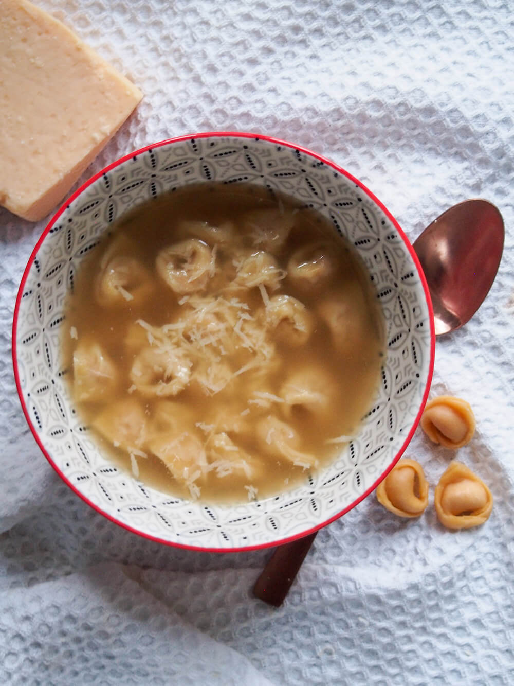 bowl of tortellini in brodo topped with parmesan