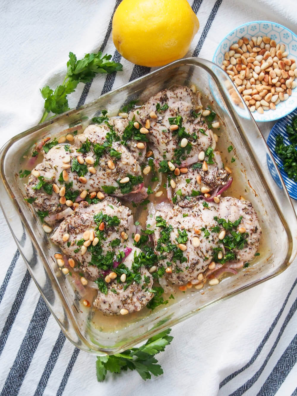 za'atar chicken in baking dish with lemon and pine nuts above dish