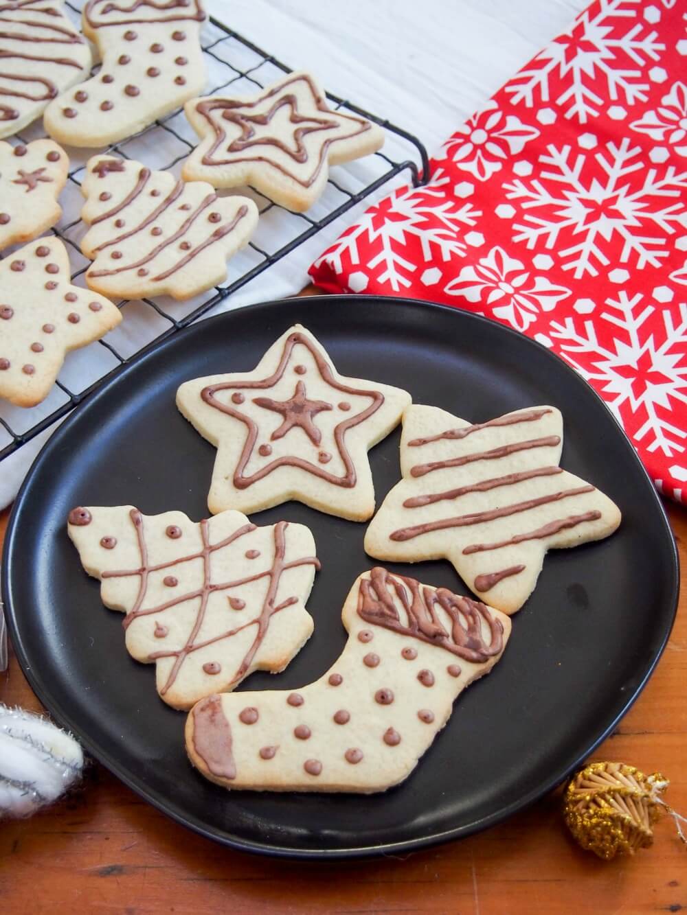 Plate of German ginger cookies (ingwerplätchen) with more on cooling rack behind and festive material in other corner