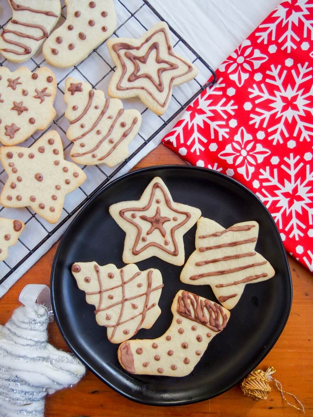Plate of German ginger cookies (ingwerplätchen) with more on cooling rack behind and festive decoration and material to side