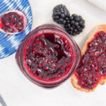 jar of blackberry jam from overhead with some on bread to side