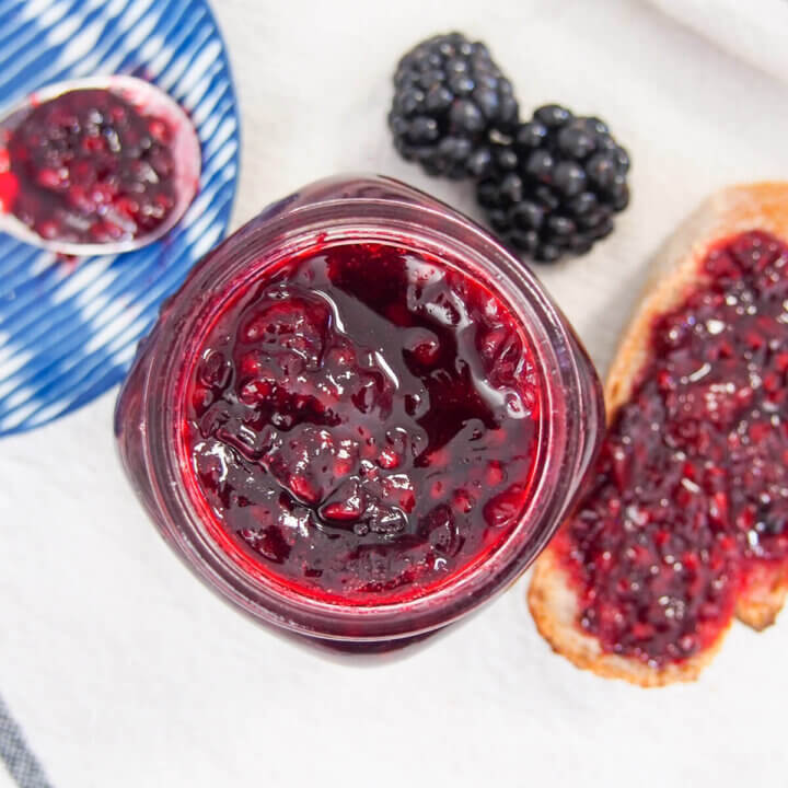 jar of blackberry jam from overhead with some on bread to side