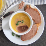 chicken liver pate in dish with some spread on bread to side and a little on knife to other side of bowl